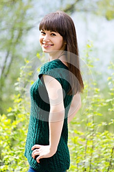 Beautiful young woman in park wearing knitted green blouse