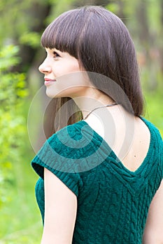 Beautiful young woman in park wearing knitted green blouse