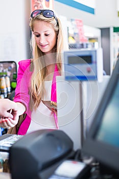 Beautiful young woman paying for her groceries at the counter