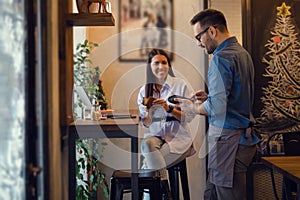 Beautiful young woman paying for her order with a credit card in a restaurant. Front focus