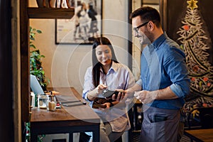 Beautiful young woman paying for her order with a credit card in a restaurant. Front focus