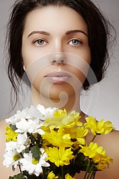 Beautiful young woman with perfect clean shiny skin, natural fashion makeup with spring flowers. Close-up woman, fresh spa look