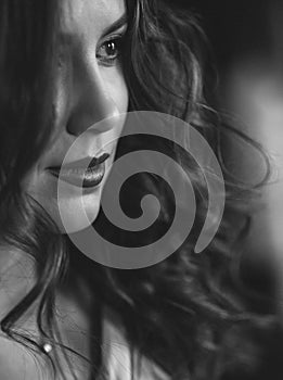 Beautiful young woman with perfect dark curly hair and beautiful make-up with puffy red lips. Close-up. Black and white art photo