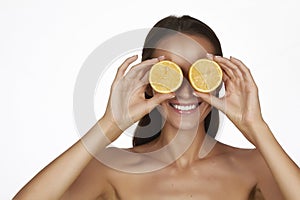 Beautiful young woman with perfect healthy skin and long brown hair day makeup bare shoulders holding orange lemon grapefruit