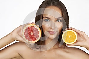 Beautiful young woman with perfect healthy skin and long brown hair day makeup bare shoulders holding orange lemon grapefruit