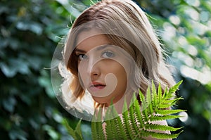 Beautiful young woman with perfect skin  posing front of plant tropical green leaves background with fern