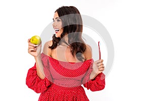 Beautiful young woman with perfect smile, sunglasses holds a green apple and tooth brush, isolated on white background