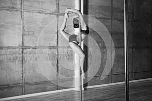 Beautiful young woman performing pole dance elements