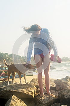 Beautiful young woman petting the dog on the beach