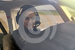 Beautiful Young Woman Pilot With Headset Looking Through The Cockpit Window