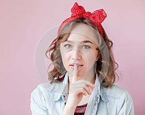 Beautiful young woman with pin-up make-up and hairstyle. Studio shot on pink background