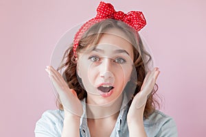 Beautiful young woman with pin-up make-up and hairstyle. Studio shot on pink background