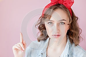 Beautiful young woman with pin-up make-up and hairstyle. Studio shot on pink background