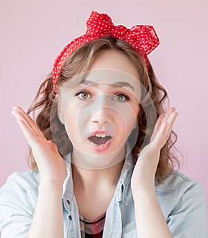 Beautiful young woman with pin-up make-up and hairstyle. Studio shot on pink background