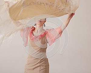 Beautiful young woman in a pink and beige dress dancing flamenco with a shawl. A scarf flutters in her hands