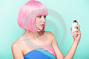 beautiful young woman with pink bob cut holding coloring hair spray