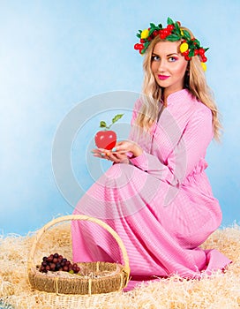 Beautiful young woman in a pink dress sitting in a hay