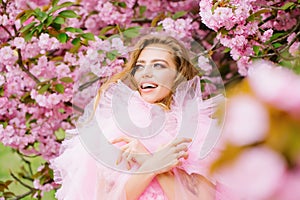 Beautiful young woman in pink glamour dress with smiling face in spring flowers bloom park