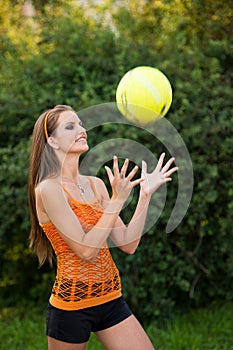 Beautiful young woman playing with ball outdoor in park