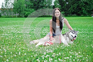 Beautiful young woman playing with funny husky dog outdoors at park