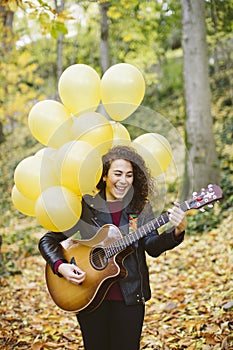 Beautiful young woman playing guitar on forest.