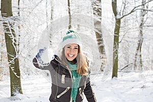 Beautiful young woman playing with a snowball outside in a fores