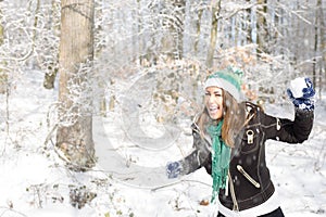 Beautiful young woman playing with a snowball outside in a fores