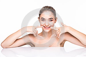 Beautiful young woman pointing on her perfect white teeth isolated on white background. Health care concept.