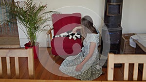 Beautiful young woman in polka-dot dress stroking cute black and white cat in a country house