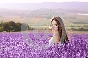 Beautiful young woman portrait in lavender field. Attractive brunette girl with long healthy hair style enjoying countryside life.