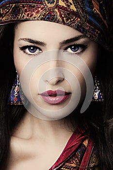 Beautiful young woman portrait in oriental style with colorful scarf and earrings