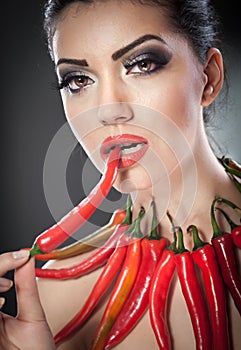 Beautiful young woman portrait with red hot and spicy peppers, fashion model with creative food vegetable make up