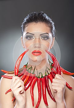 Beautiful young woman portrait with red hot and spicy peppers, fashion model with creative food vegetable make up