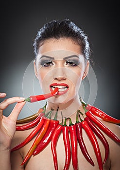 Beautiful young woman portrait with red hot and spicy peppers, fashion model with creative food vegetable make up