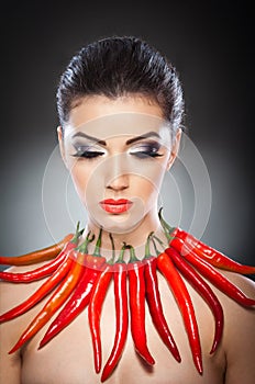 Beautiful young woman portrait with red hot and spicy peppers