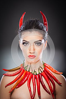 Beautiful young woman portrait with red hot and spicy peppers, fashion model with creative food vegetable make up