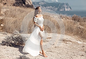 Beautiful young woman portrait in a white dress enjoying in the hay field. Natural beauty female. Romantic bride