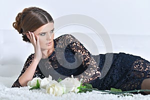 Beautiful young woman posing on bed with flowers