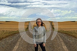 Beautiful young woman posing in front of two ways trying to make a decision about her future. Cloudy sky