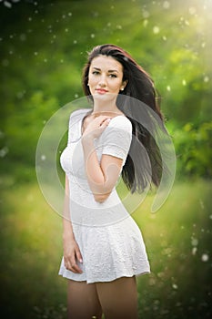 Beautiful young woman posing in a summer meadow. Portrait of attractive brunette girl with long hair relaxing in nature, outdoor