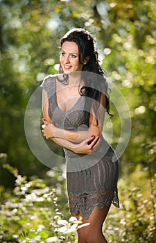 Beautiful young woman posing in a summer meadow. Portrait of attractive brunette girl with long hair relaxing in nature, outdoor