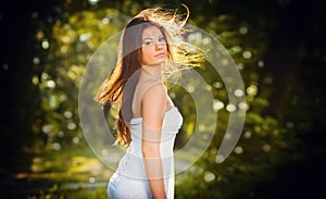 Beautiful young woman posing in a summer meadow. Portrait of attractive brunette girl with long hair relaxing in nature, outdoor