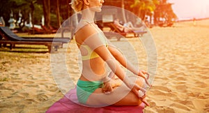 Beautiful young woman practic yoga at the beach. Early morning exercise photo