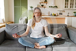 Beautiful young woman practicing meditation at home