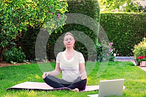 Beautiful young woman practicing yoga in garden outdoors