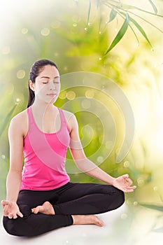 Beautiful young woman practicing yoga, sitting in a lotus position