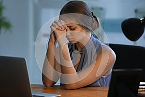 Beautiful young woman praying in office