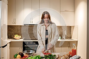 Beautiful young woman preparing vegetable vegan salad in the kitchen. Healthy food and diet concept lifestyle. Cook at home