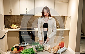 Beautiful young woman preparing vegetable vegan salad in the kitchen. Healthy food and diet concept lifestyle. Cook at home