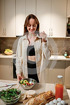 Beautiful young woman preparing vegetable vegan salad in the kitchen. Healthy food and diet concept lifestyle. Cook at home